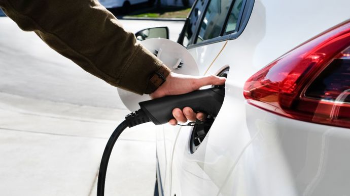 Person plugging EV charger into electric car